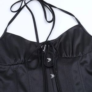 Detail of black satin halter top featuring a silk texture and metal front buttons