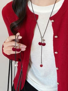 Detail of red flocked cherry pendant necklace with silver metal stem on model