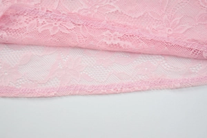 Primer plano detallado de la textura de encaje rosa y costuras finas en el top ajustado