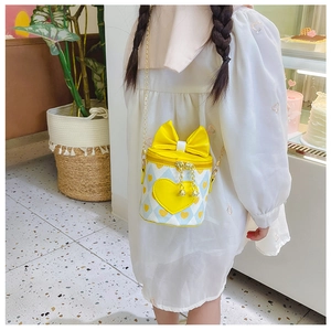 Close-up of yellow PU leather heart bucket bag for girls with bow and gold chain strap