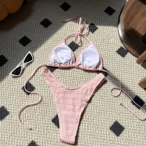 Detailed view of pink smocked bikini set with drawstring details on a beige carpet