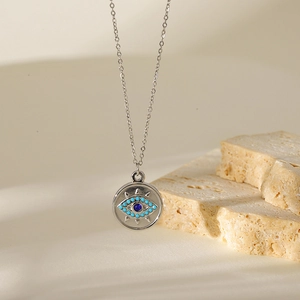 Detail of evil eye pendant with blue bead on silver chain against stone base