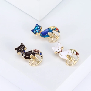 Three elegant enamel cat brooches in blue, black, and white with floral gold accents