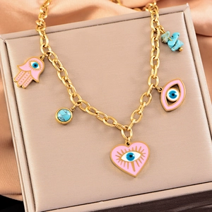 Golden titanium steel jewelry set with evil eye charms and pink heart on champagne silk
