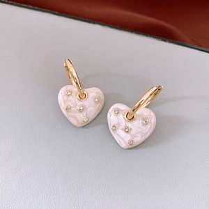 Detailed macro view of pink marble heart pendant earrings with gold metal hoops