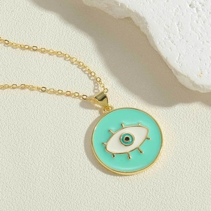 Macro view of a gold-tone necklace featuring a mint green evil eye pendant and delicate chain