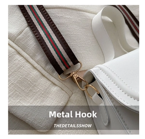 Detail of gold metal hook and red-green striped woven strap on white leather shoulder bag