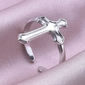 Close-up of a silver stainless steel cross ring on elegant pink silk background