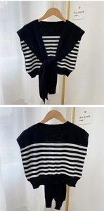 Detailed knit texture of a black and white striped shawl wrap with a stylish knotted front