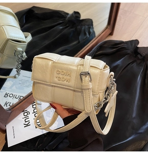 Détail du petit sac bandoulière tressé crème avec chaîne argentée et gaufrage