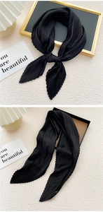 Detailed view of black pleated scarf with fine silk texture and elegant knot style