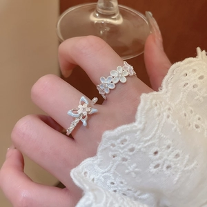 Macro detail of elegant flower and bow rings with diamonds and blue enamel on finger