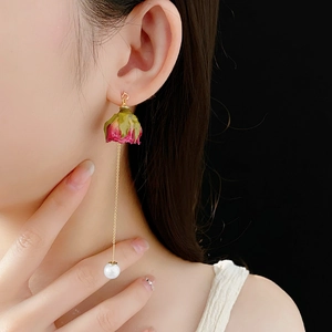 Détail de la boucle d'oreille longue avec bouton de rose, chaîne d'or et perle