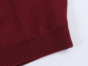 Detail of burgundy knitted fabric showing the fine ribbed hem and stitching texture