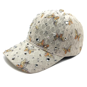 Detailansicht der beigen Spitzen-Baseballkappe mit Schmetterlingsdruck und Glitzer