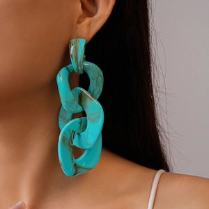 Detailed close-up of teal acrylic chain link earring with marble texture on female model