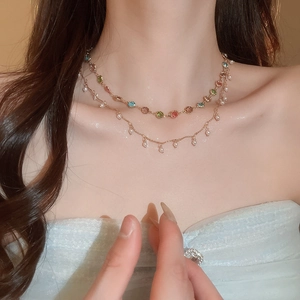 Detail einer doppelreihigen Goldkette mit bunten Kristallen und kleinen weißen Perlenanhängern