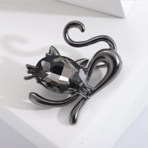 Detailed view of an elegant black crystal cat brooch with faceted gemstone on a white pedestal