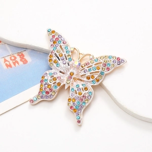 Macro de bijou papillon avec strass colorés sur une pierre et fond blanc épuré