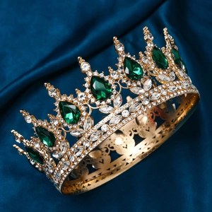 Close-up of golden crown featuring large green teardrop gems and sparkling crystals