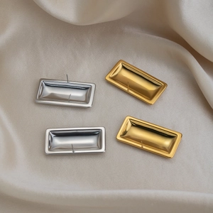 Rectangular geometric stud earrings in gold and silver finish on silk fabric background
