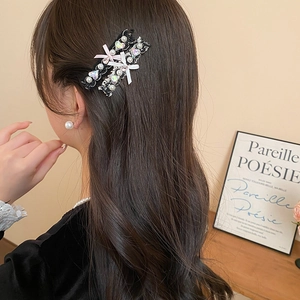 Detailed side view of black lace hair clip with pearls and heart gemstone decoration