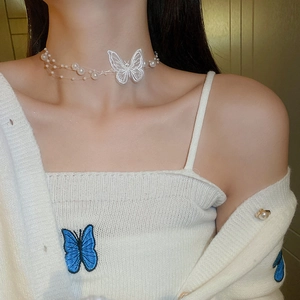 Gros plan d'un collier papillon en organza blanc avec perles porté par un mannequin