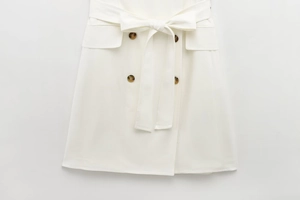 Detail of white blazer dress featuring double-breasted buttons and self-tie waist belt