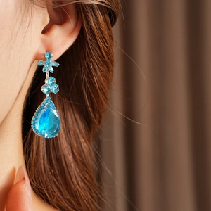 Gros plan de boucles d'oreilles fleur en zircon bleu avec cristal goutte sur mannequin