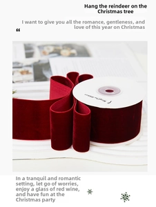 Detail of dark red velvet ribbon on white spool for Christmas gift wrapping decor