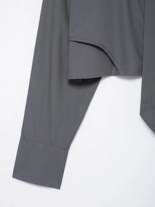 Detail of grey poplin shirt featuring wide cuffs and an asymmetric layered hemline