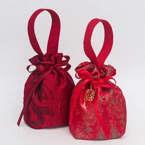 Detail of red wedding candy bag with brocade floral texture and golden Xi pendant