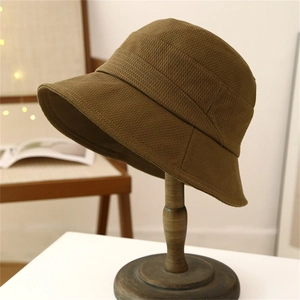 Olive green bucket hat with corduroy texture on a wooden stand for autumn travel