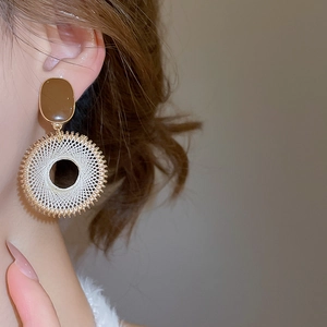 Close-up of Bohemian woven circle earrings with gold metal base and geometric details