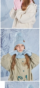 Detailed knit texture of children's winter hat with fluffy pom pom and scarf in the snow