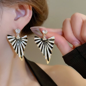 Vue macro de boucles d'oreilles triangulaires rétro en émail noir et blanc et zircons