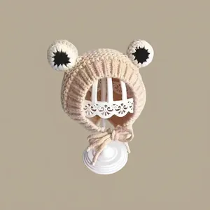 Close-up of knit frog baby hat with large eyes and secure chin straps for winter