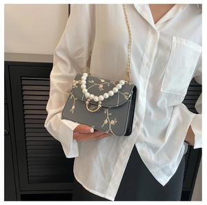 Close-up of elegant small square bag featuring pink floral embroidery and pearl handle
