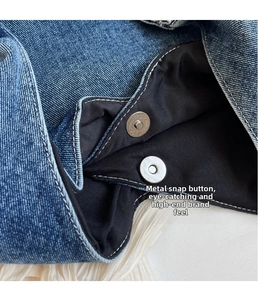 Detail of silver magnetic buckle closure and durable denim fabric on trendy shoulder bag