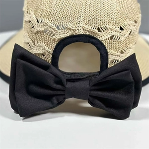 Detail of knitted hollow texture on beige straw hat with large black ribbon bow