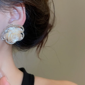 Close-up of elegant white floral stud earrings with silver edges worn by a female model