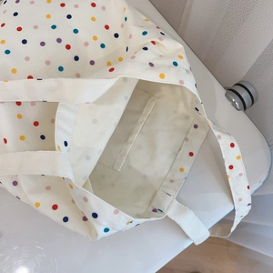 Close-up of colorful polka dot canvas tote bag interior with functional side pocket