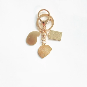 Artistic gold-plated keychain with textured charms and lobster clasp on white background