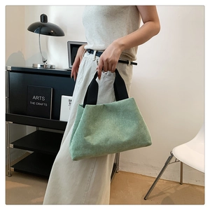 Détail d'un sac à main en velours côtelé vert clair avec anses noires dans un décor chic