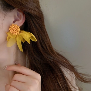 Elegant yellow mesh flower earrings with silver needles and beaded center on a model