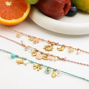 Colorful woven cord bracelets with gold celestial and floral charms on white background