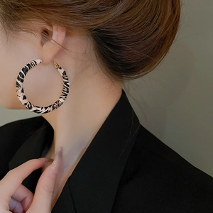 Close-up of model wearing large leopard print hoop earrings with vintage fashion style