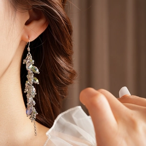 Detail of bohemian long tassel earrings with clear faceted crystals and silver hooks