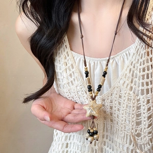 Détail du pendentif étoile en céramique bohème avec pompons en perles et cordon tissé