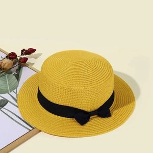 Detailed close-up of yellow straw boater hat with black ribbon bow on warm background